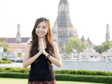 Attractive asian woman greeting with Temple of Dawn Wat Arun bac clipart