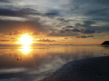 The sun sets over beach with beautiful reflection clipart