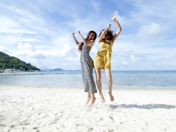 Mulher pulando juntos na praia de areia com fundo azul céu — Fotografia de Stock