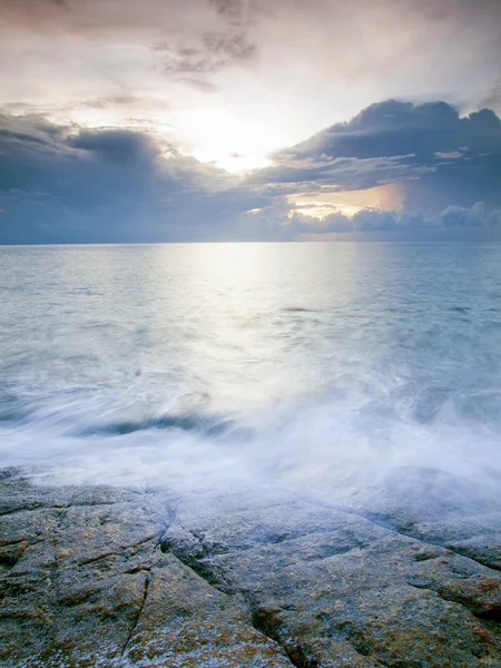 Пейзаж моря с волной и скалой на закате . — стоковое фото