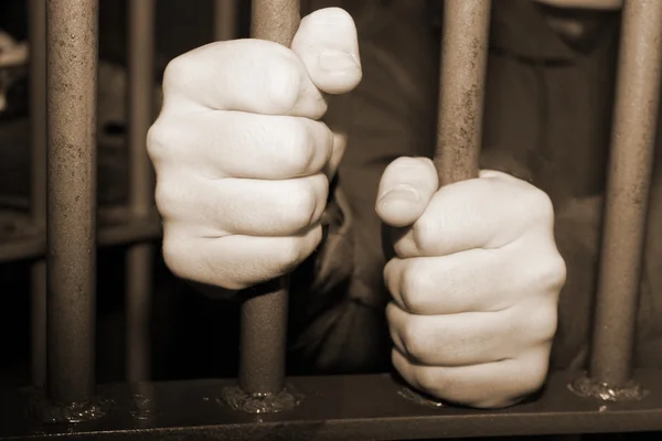 Man's hands behind metal bars — Stock Photo, Image