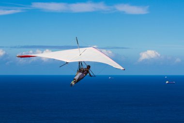 Hang Gliding over a deep blue Ocean on a clear day clipart