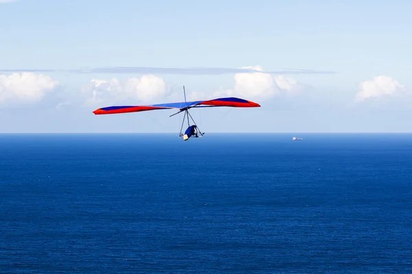 Hängglidare som flyger över det blå havet på en vacker dag Stockfoto