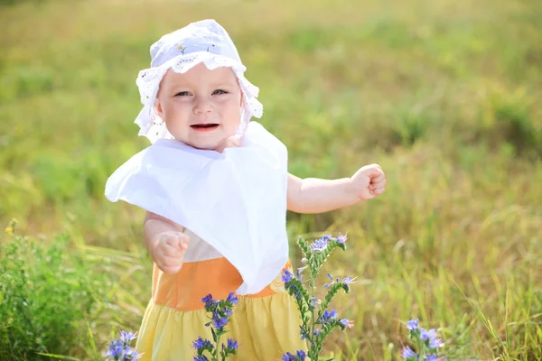 Lille baby pige gå ved grøn mark på solrig dag - Stock-foto