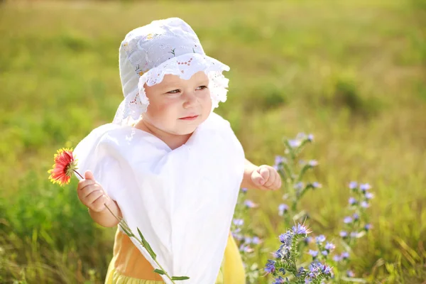 Criança triste com flor no campo verde — Fotografia de Stock
