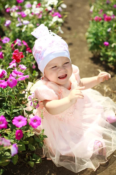 Upset little baby in flowers field — Stock Photo, Image