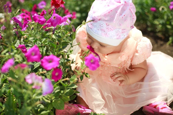 Маленькая девочка наслаждается ароматом цветка — стоковое фото