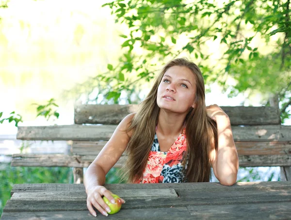 Schöne junge Frau genießt einen Sommertag auf Holzbank — Stockfoto