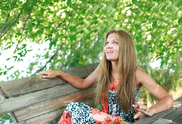 Beautiful young blonde woman enjoying a summer day on bench — Stock Photo, Image