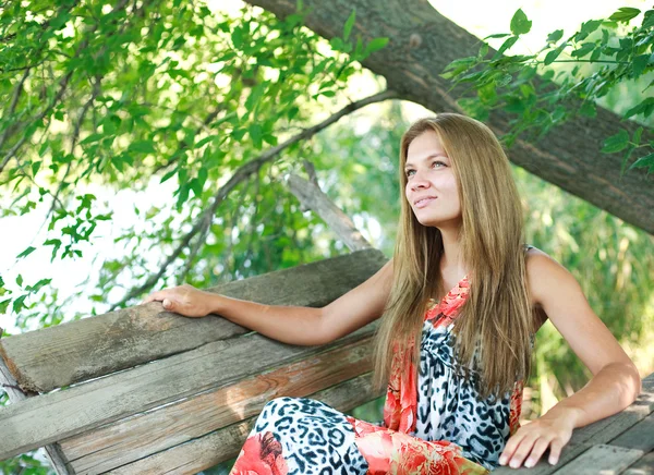 Schöne junge Blondine genießt einen Sommer auf Holzbank — Stockfoto