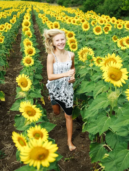Glückliches junges blondes Mädchen läuft im Feld der Sonnenblumen — Stockfoto