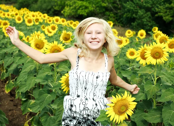 Glückliches junges Mädchen springt und Spaß im Feld der Sonnenblumen hat — Stockfoto