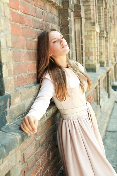 Leidenschaftliches blauäugiges junges Mädchen träumt in der Nähe einer alten Ziegelmauer — Stockfoto