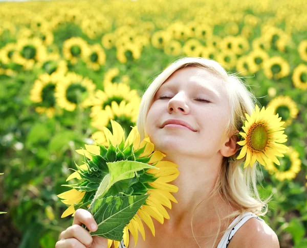 Ung flicka i fältet av solrosor njuta en sommardag — Stockfoto