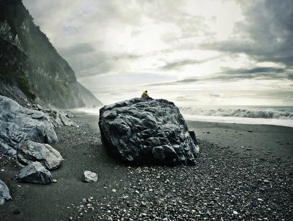 Mann auf dem Felsen beobachtet das Meer Stockbild