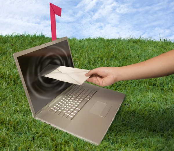 Laptop computer and hand with letter on grass — Stock Photo, Image