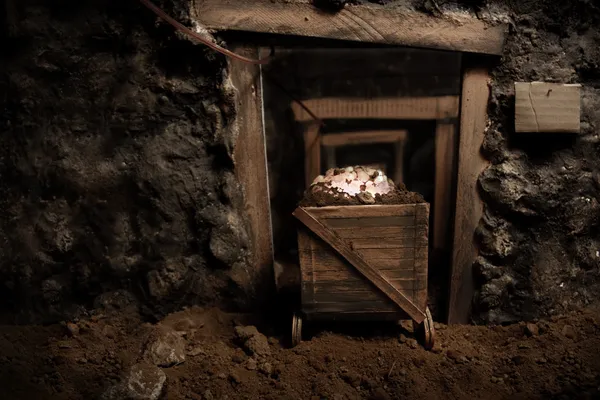 Dentro de uma velha mina com um carrinho de mineração cheio de pedras brilhantes — Fotografia de Stock
