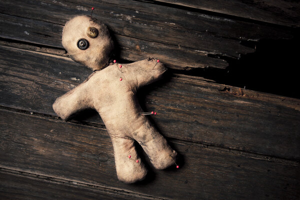 Creepy voodoo doll on wooden floor