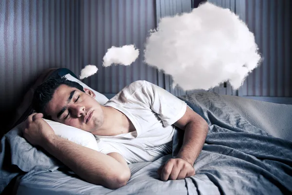 Человек комфортно мечтает в своей постели с облаком Стоковое Фото