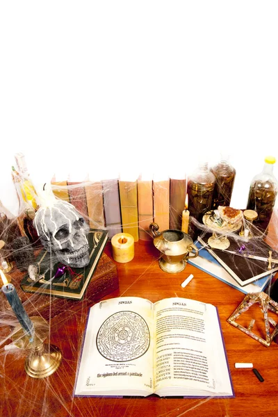 Table full of witchcraft related objects and cobweb isolated on white — стоковое фото