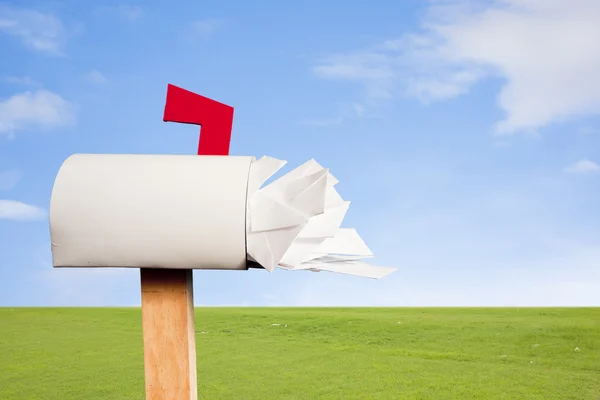 Mail box overflowing with mail against sky and grass — Stock Photo, Image