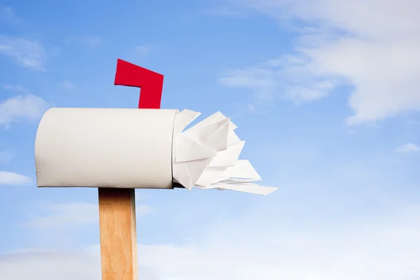 Mail box overflowing with mail against sky — Stock Photo, Image