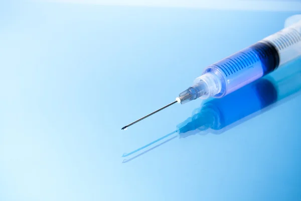 Close up of a syringe on glossy background — Stock Photo, Image