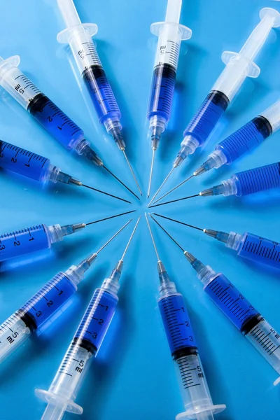 Jeringas médicas formando un círculo sobre fondo azul —  Fotos de Stock