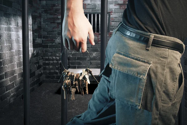 Prison guard with keys walking outside dark prison cell — Stockfoto