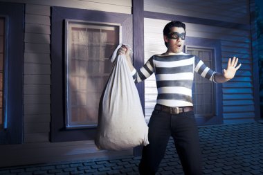 Thief walking on the roof of a house at night clipart