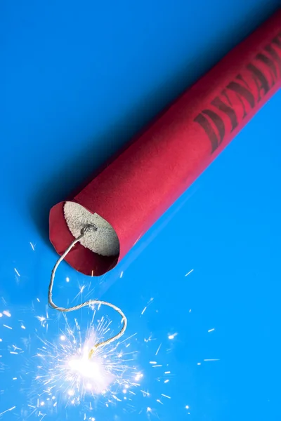 Lit dynamite stick on a blue background — Stock Photo, Image