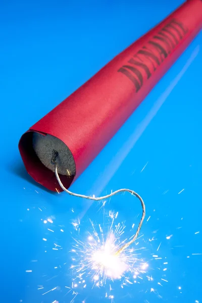 Lit dynamite stick on a blue background — Stock Photo, Image