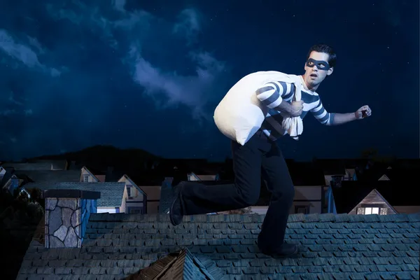 Thief on the roof running away at night — Stock Photo, Image