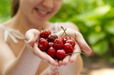 She holds a handful of red cherries clipart