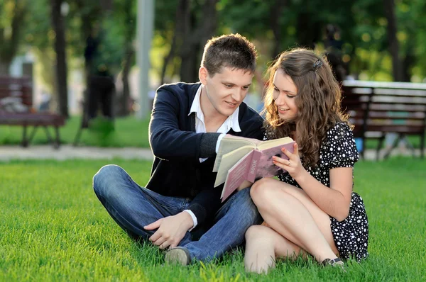 少年と少女は草の上に座って本を読んで — ストック写真