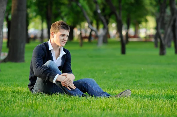 Killen sitter på gräset — Stockfoto