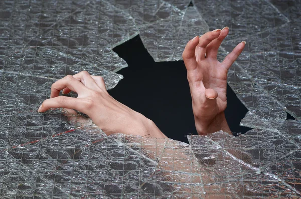 Zwei Hände bahnen sich ihren Weg durch das zerbrochene Glas — Stockfoto