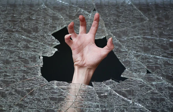 Hand make their way through the broken glass — Stock Photo, Image