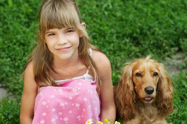 La niña está sentada en la hierba con el perro — Foto de Stock