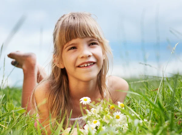 Das lächelnde Mädchen liegt auf der Wiese — Stockfoto