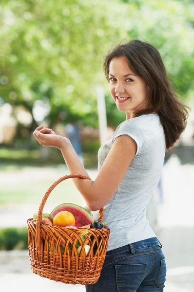 Flicka med en korg med frukt och grönsaker — Stockfoto