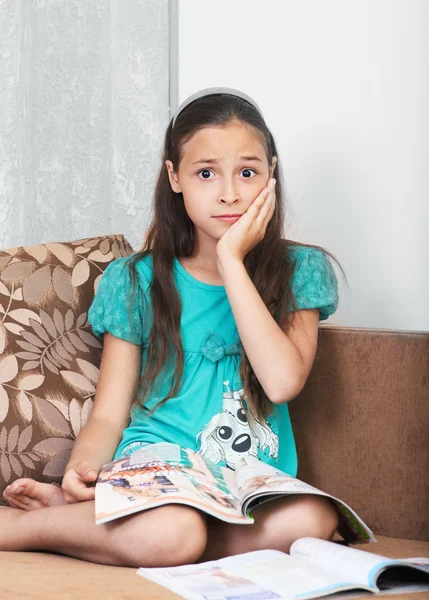 The upset girl is sitting on the sofa — Stock Photo, Image