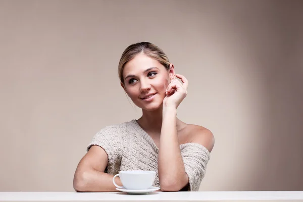 Schöne, glückliche junge Frau im Pullover mit einer Tasse aromatischem Haarschopf — Stockfoto