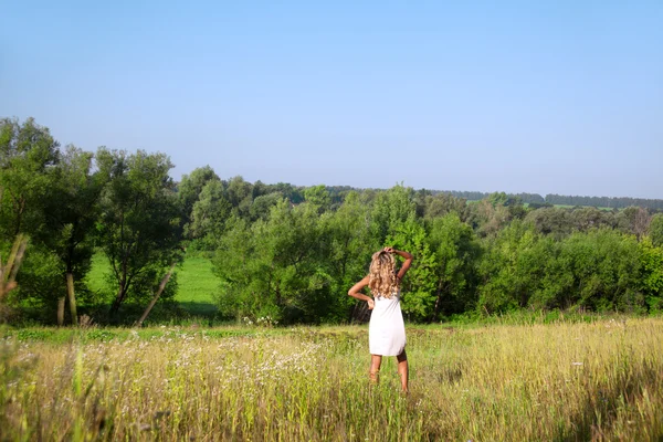 Mädchen in weißem Kleid läuft an einem Sommertag über die Wiese — Stockfoto