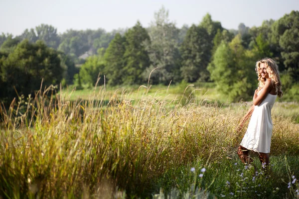 Girl in white dress walking on the meadow in summer day — Stock Photo, Image