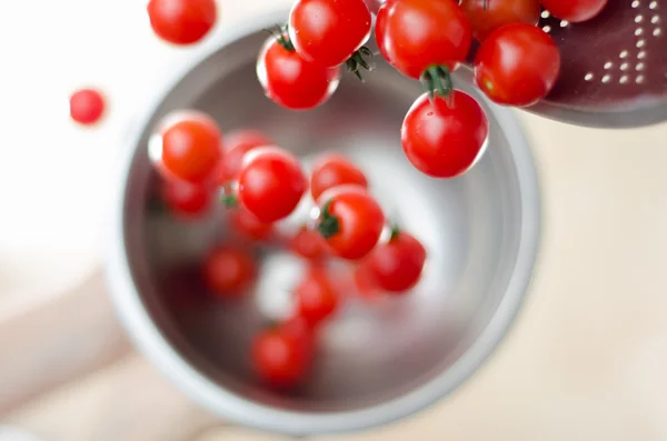 Wiśniowe pomidory upadki z metalu durszlak do metalowej miski — Zdjęcie stockowe