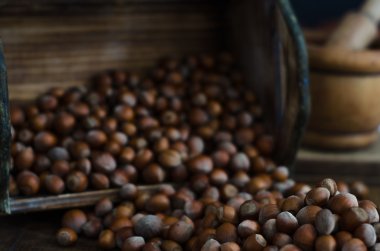 Hazelnuts in Wooden Box Poured Out onto Oak Table clipart