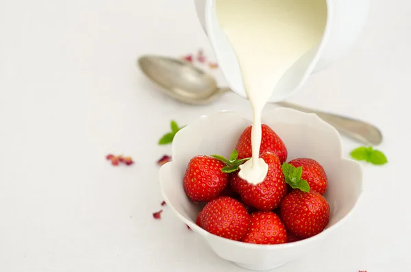 Crème van een kruik gieten over verse aardbeien — Stockfoto