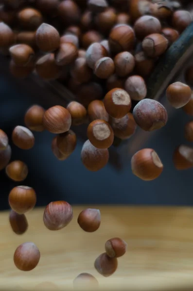 Lískové ořechy v pohybu naskakují do bambusové mísa — Stock fotografie