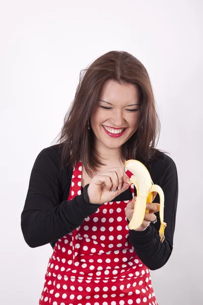 Молода жінка посміхається і чистить банан — стокове фото